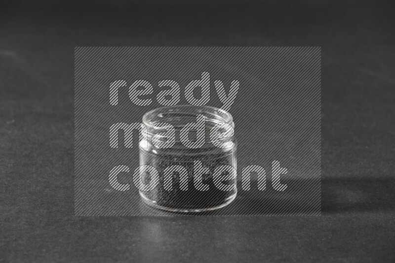 وعاء زجاجي ممتلئ ببذور حبة البركة علي خلفية سوداء