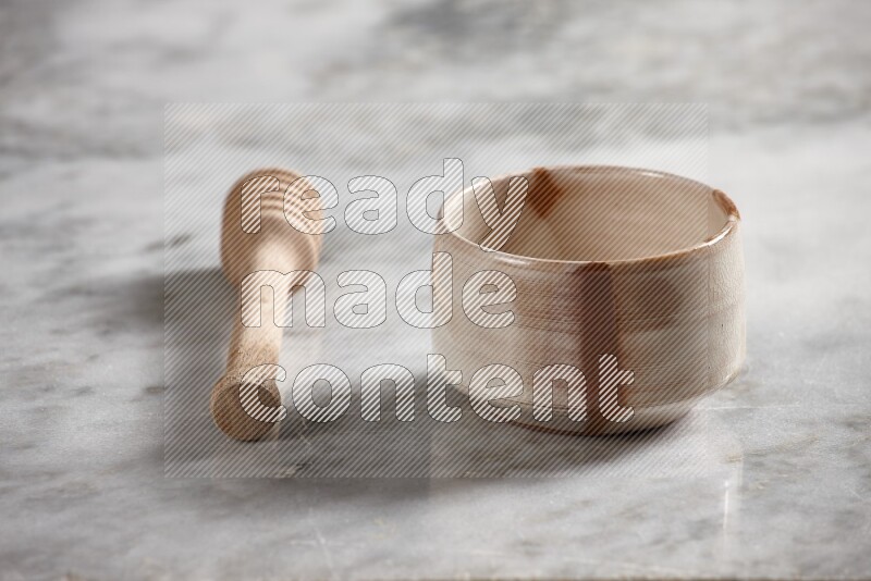 Multicolored pottery bowl with wooden honey dipper on the side on grey marble background