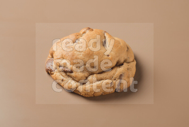 a whole chocolate chip cookie on a brown background