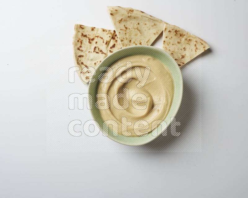 plain Hummus in a green plate on a white background