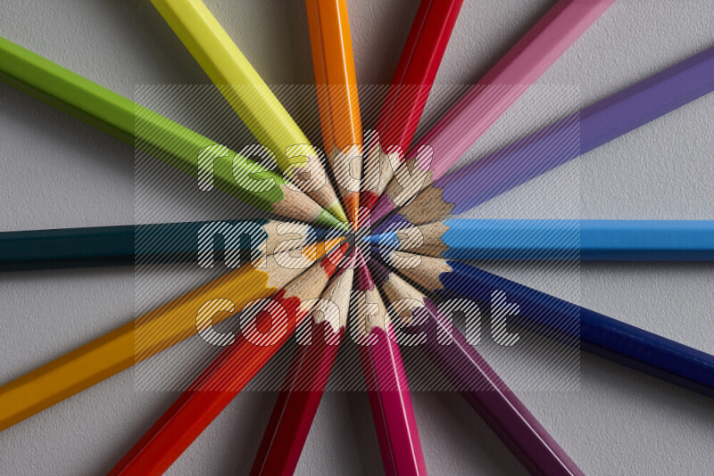An arrangement of colored pencils in different colors on grey background