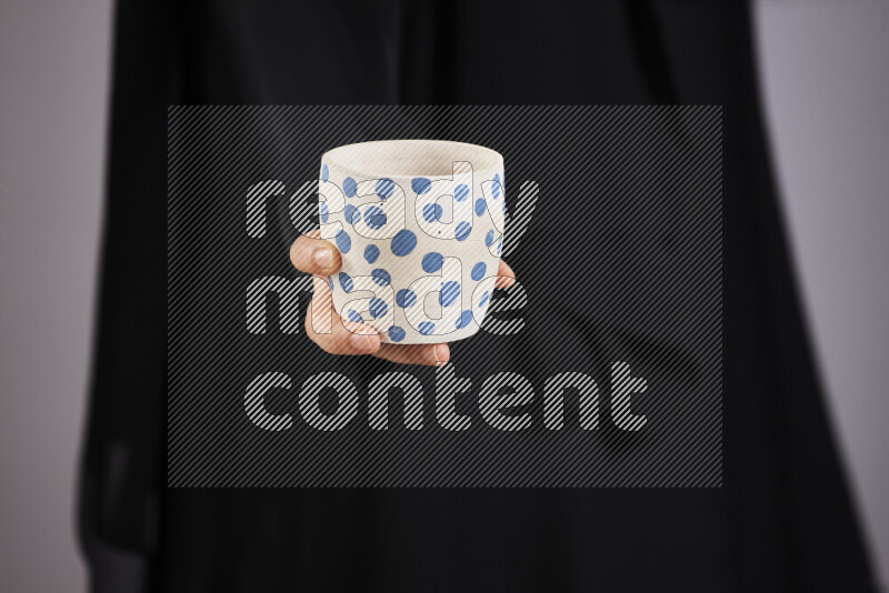 A woman in black abaya holding different pottery essentials in different positions