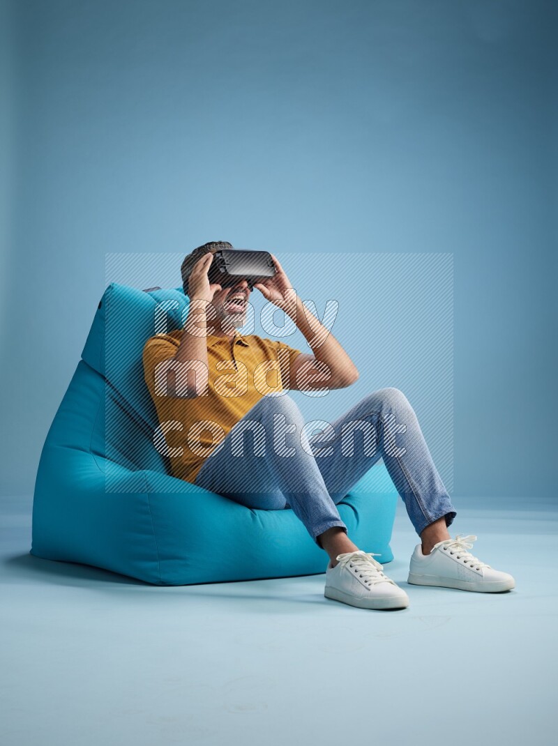 A man sitting on a blue beanbag and gaming with VR