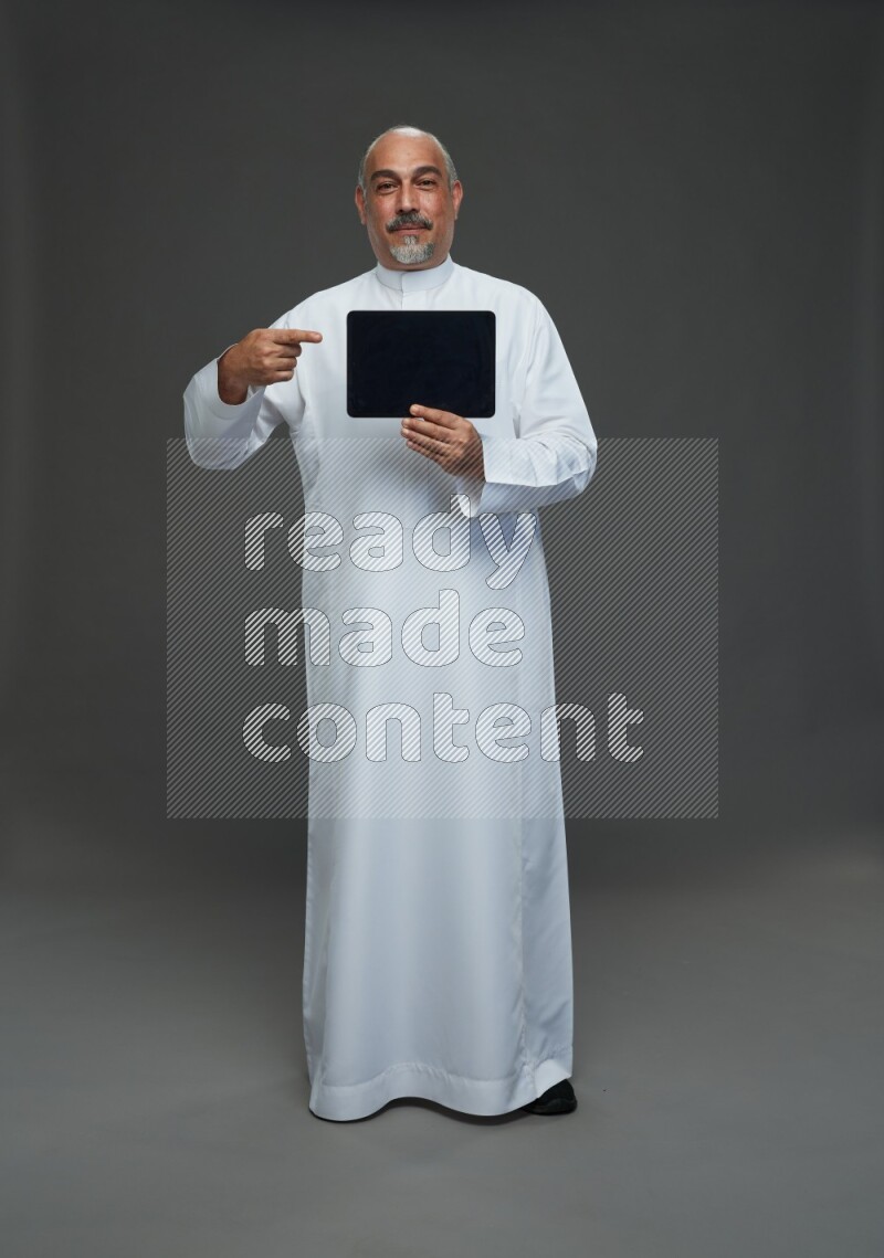 Saudi man without shomag Standing working on tablet on gray background
