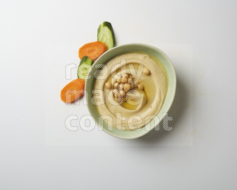 Hummus in a green plate garnished with roasted chickpeas  on a white background