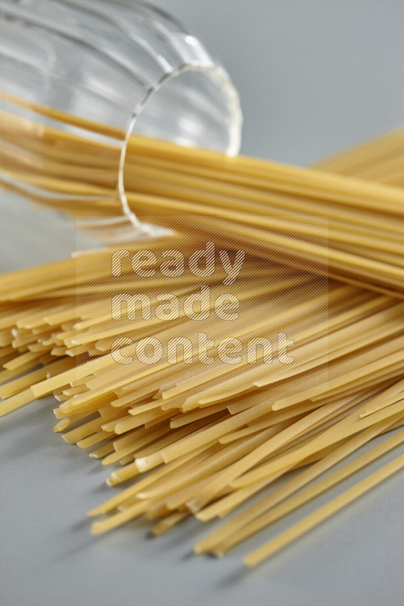 Flipped jar full of raw pasta on light blue background
