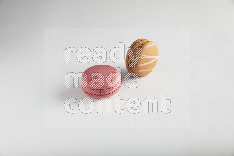 45º Shot of of two assorted Brown Irish Cream, and Pink Raspberry macarons on white background