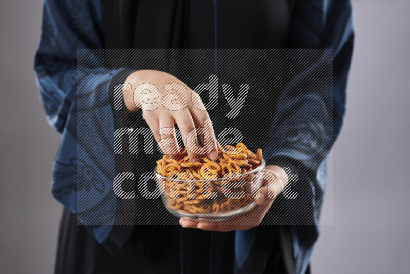 Woman in abaya holding different kinds of snacks in different positions