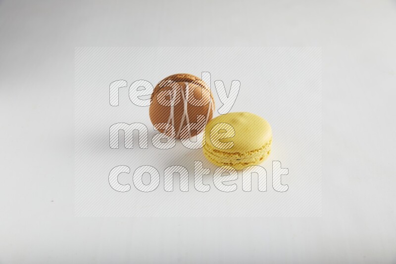 45º Shot of of two assorted Brown Irish Cream, and Yellow Lemon macarons on white background