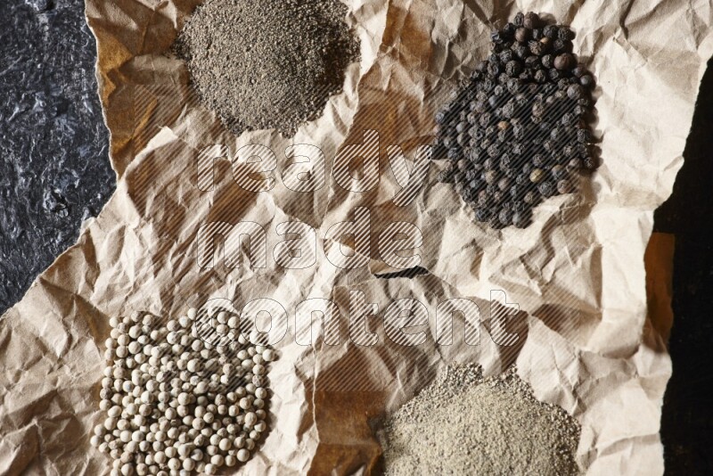 قطع من الورق ممتلئة بحبوب وبودرة الفلفل الأسود والأبيض على أرضية سوداء