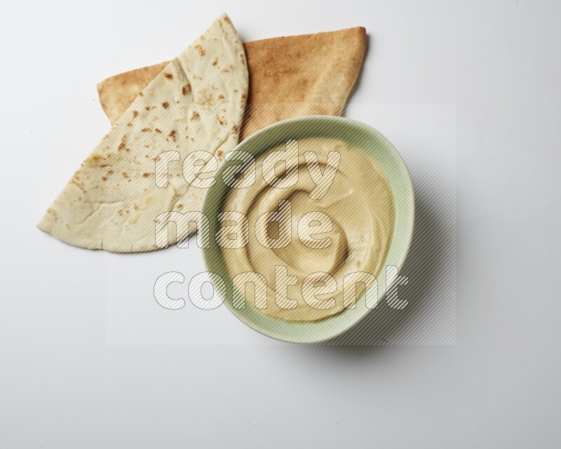 plain Hummus in a green plate on a white background