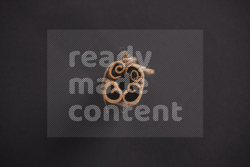 4 Cinnamon sticks stacked and bounded on black flooring