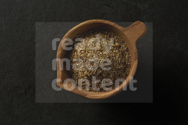 wooden round sauce bowl filled with herbs on grey textured countertop