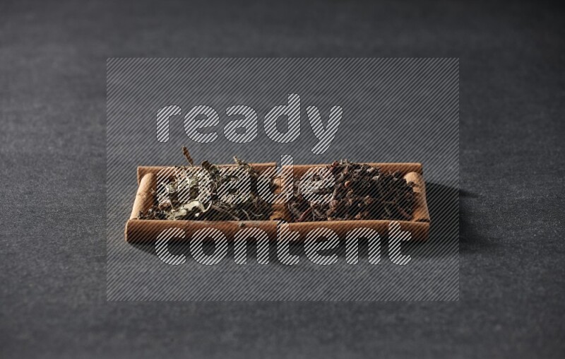 2 squares of cinnamon sticks full of cloves and dried basil on black flooring