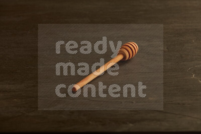 Wooden honey dipper on black slate background