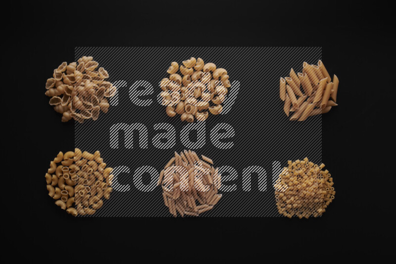 Different pasta types in bunches on black background