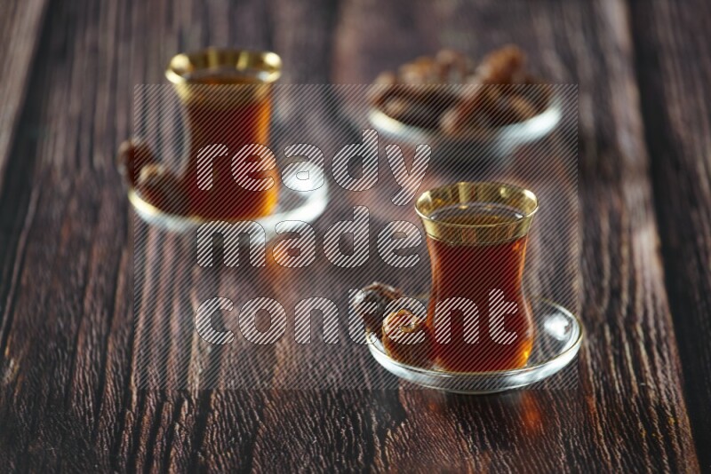 A tea glass cup with dates and coffee on wooden background