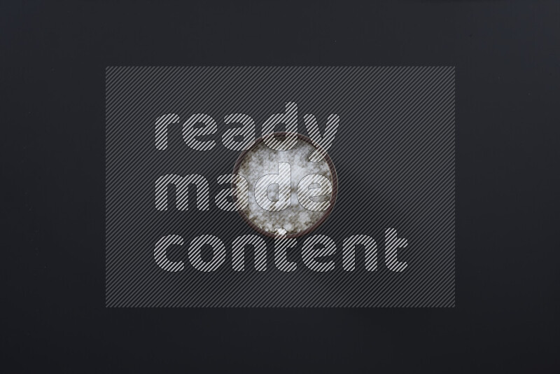 وعاء فخاري ممتلئ بملح الطعام الناعم وملح البحر الخشن على خلفية سوداء