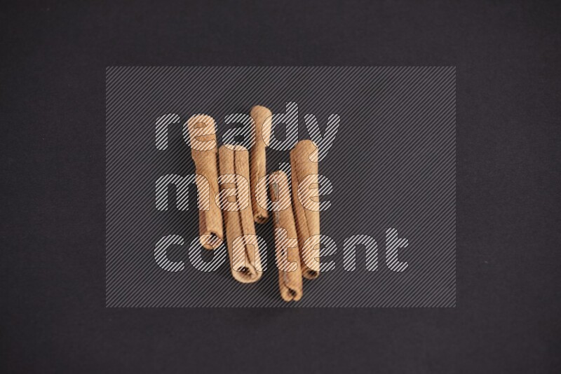 Cinnamon sticks stacked on black flooring