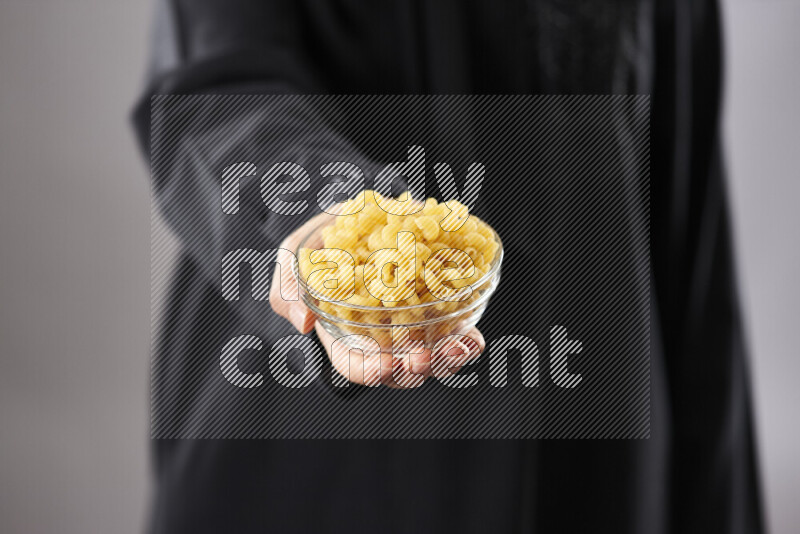 Woman in abaya holding different kinds of pasta in different positions
