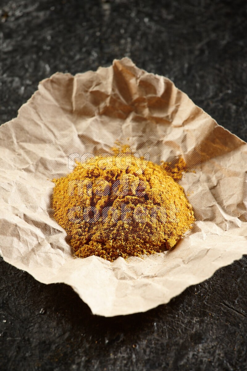 بودرة الكركم  في قطعة من الورق على خلفية سوداء