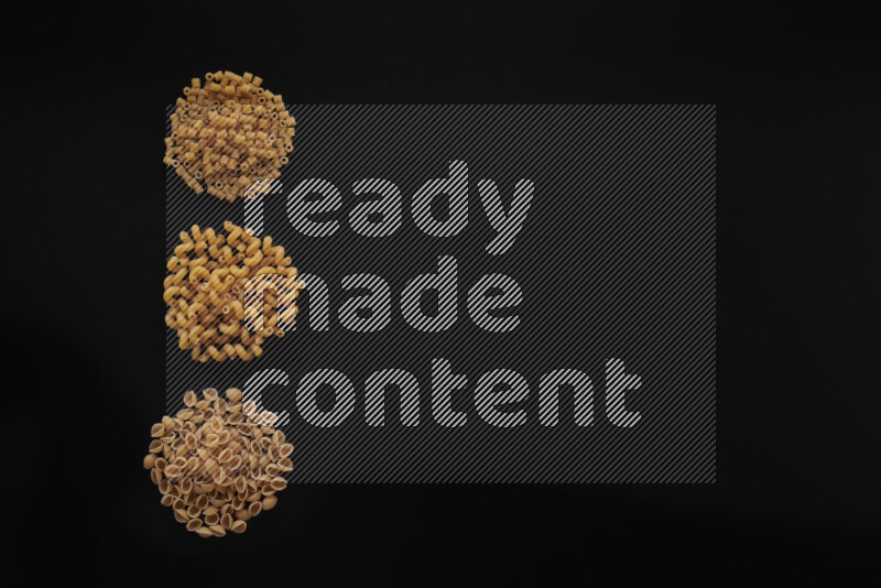 Different pasta types in 3 bunches on black background
