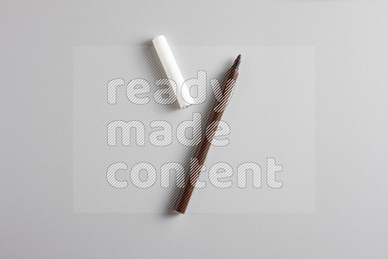 A close-up showing an open single coloring pen with a cap on grey background