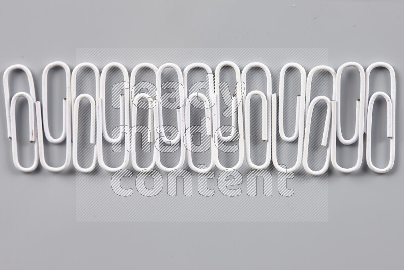White paper clips isolated on a grey background