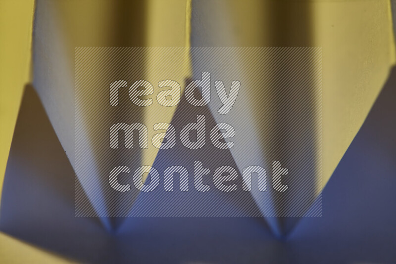 A close-up abstract image showing sharp geometric paper folds in blue gradients and warm tones