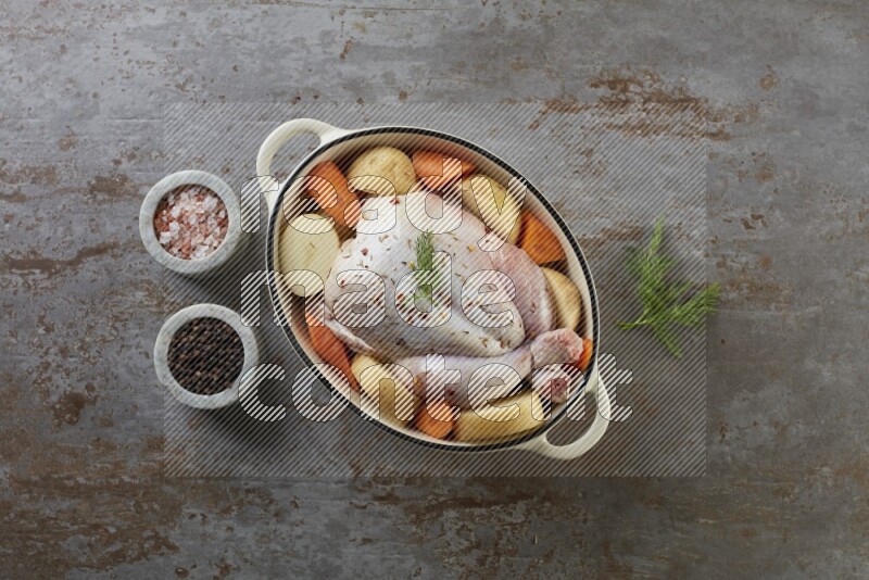 whole raw chicken on in a white ceramic pot direct on a rustic grey background