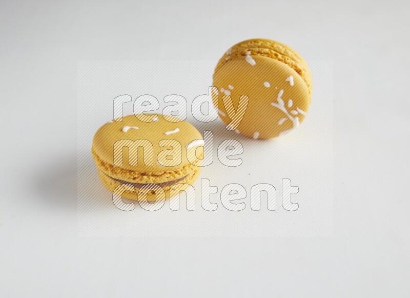 45º Shot of two Yellow Piña Colada macarons on white background