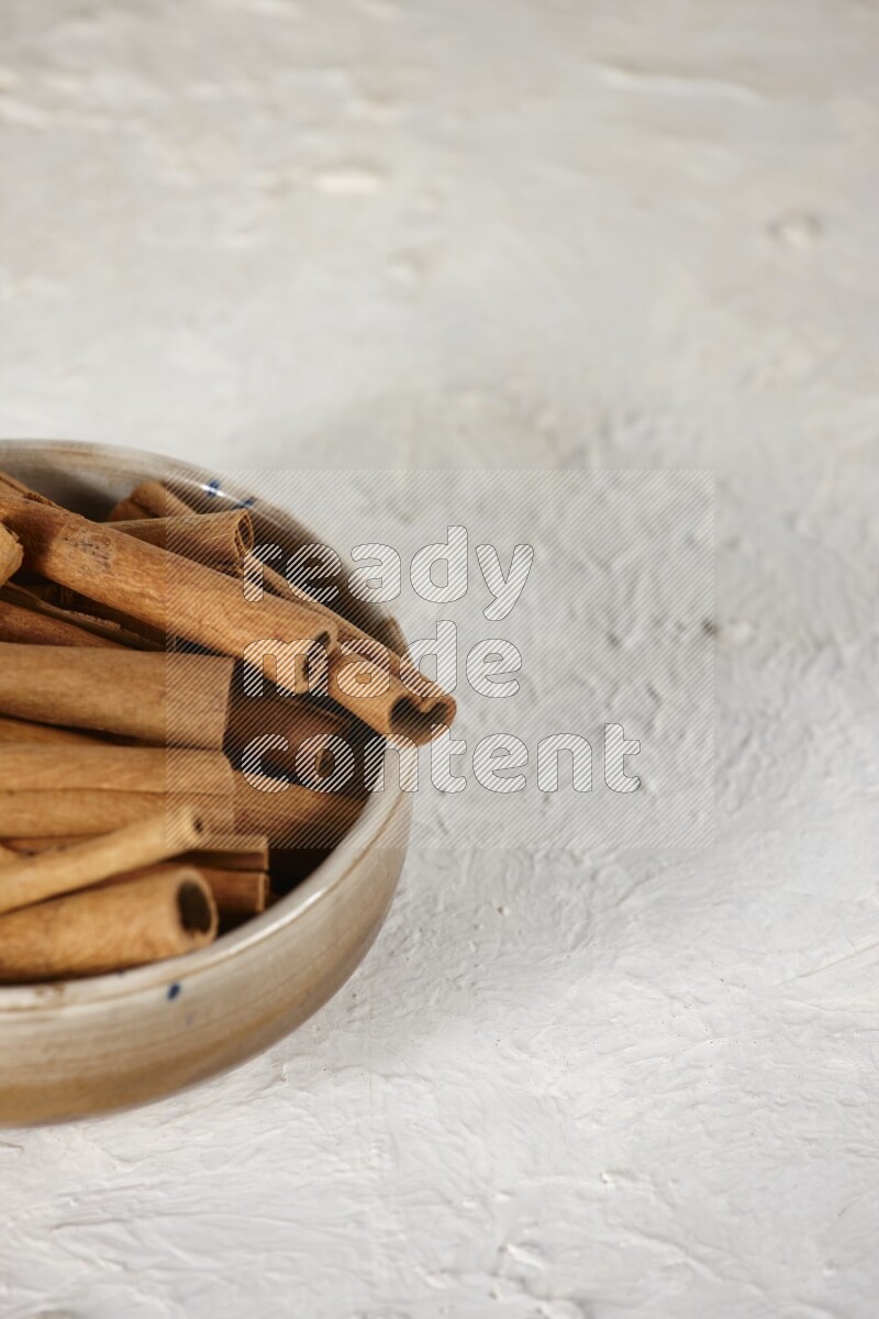 Cinnamon sticks in a ceramic bowl in different angles on white background