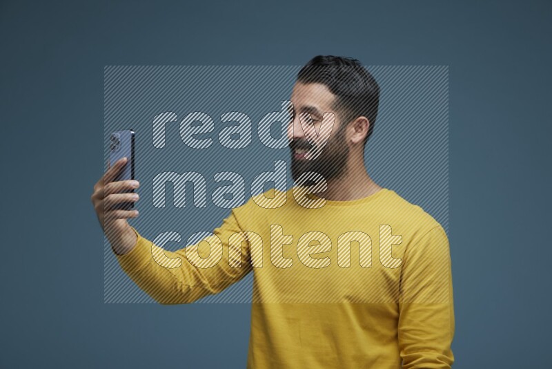 Man Taking a Selfie  in a blue background wearing a yellow shirt