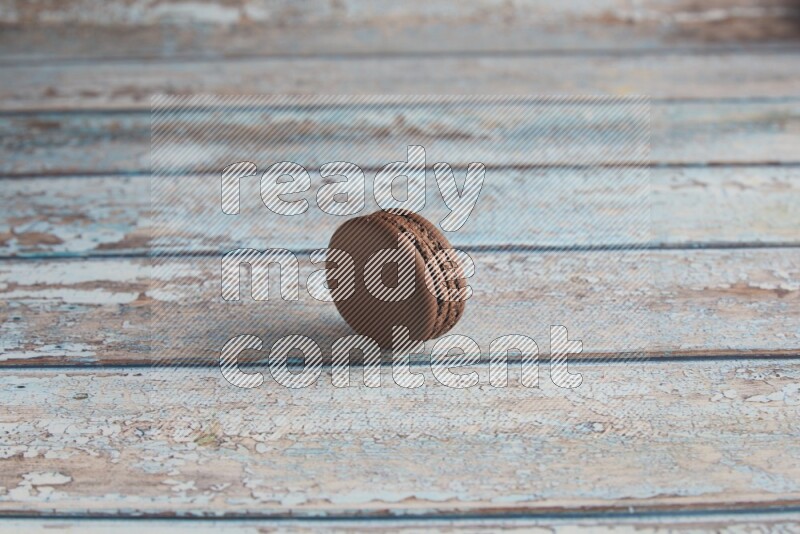 45º Shot of Brown Dark Chocolate macaron on light blue wooden background