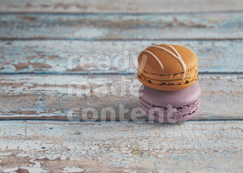 45º Shot of of two assorted Brown Irish Cream, and Purple Blueberry macarons  on light blue background