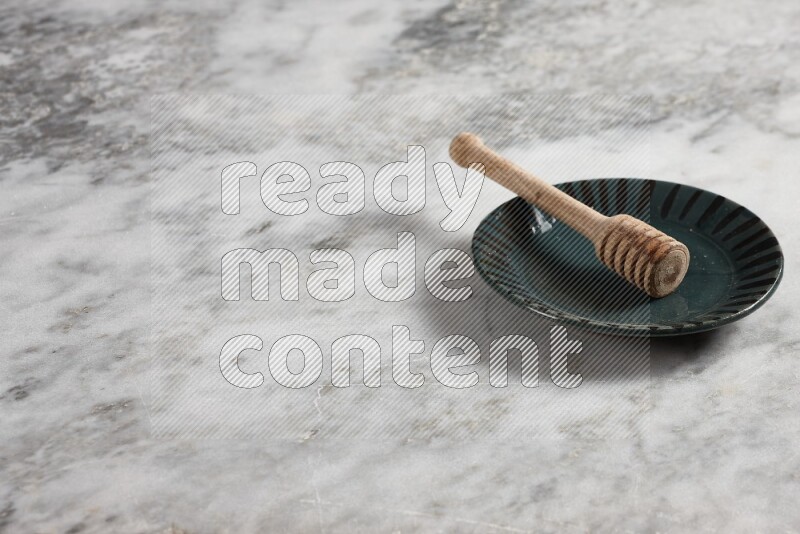 Multicolored pottery plate with wooden honey dipper in it on grey marble background