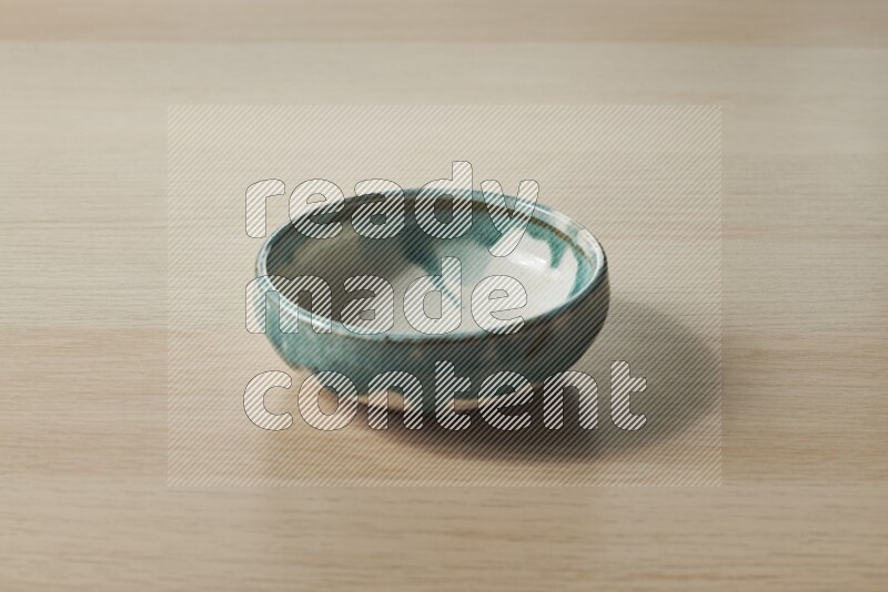 A multicolored pottery bowl on light wooden background
