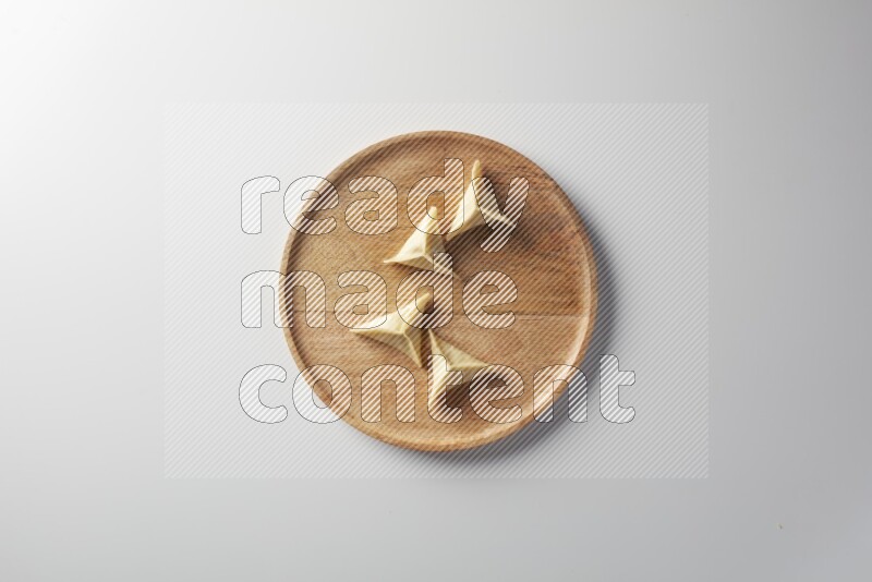 Four Sambosas on a wooden round plate on a white background
