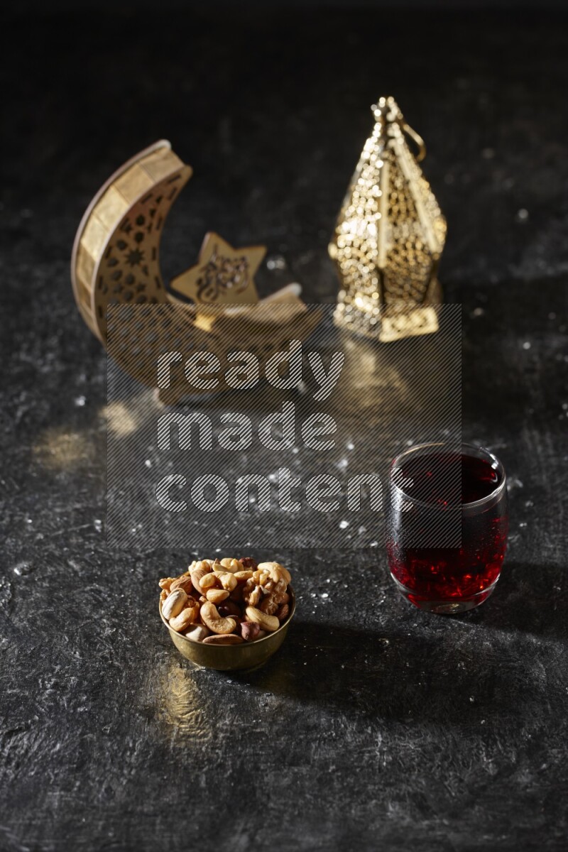 Nuts in a metal bowl with Hibiscus beside golden lanterns in a dark setup