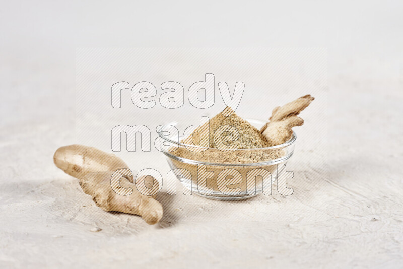 A glass bowl full of ground ginger powder on white background