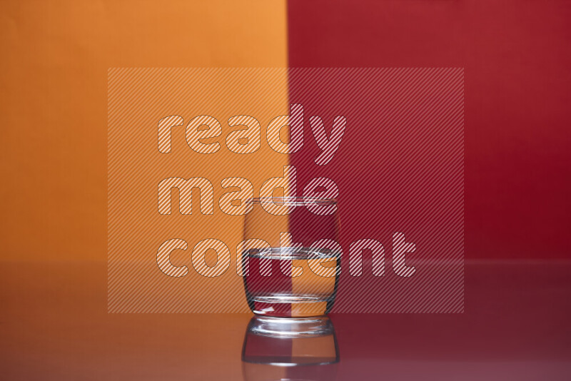 The image features a clear glassware filled with water, set against orange and red background