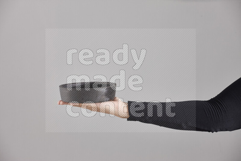 A woman in black abaya holding different pottery essentials in different positions