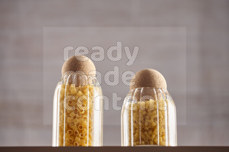 Raw pasta in glass jars on beige background