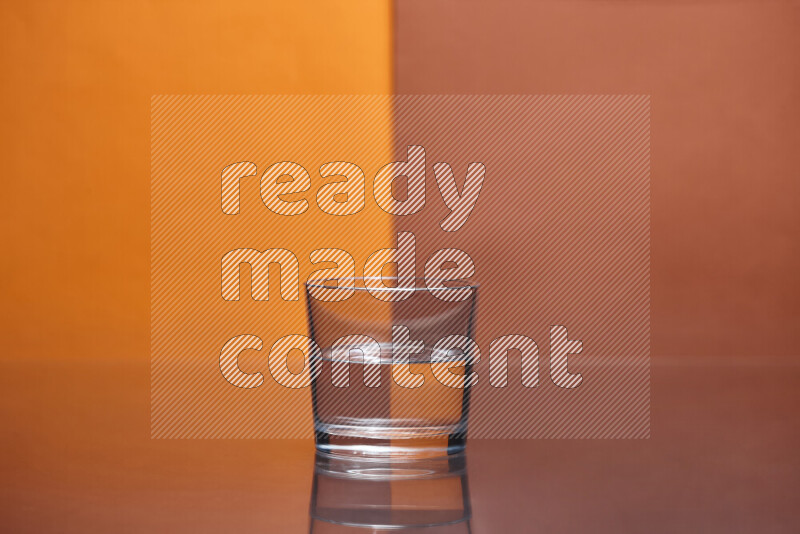 The image features a clear glassware filled with water, set against orange and dark orange background
