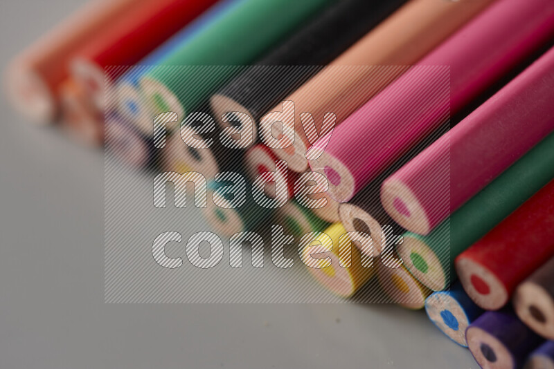 An array of colored pencils on grey background