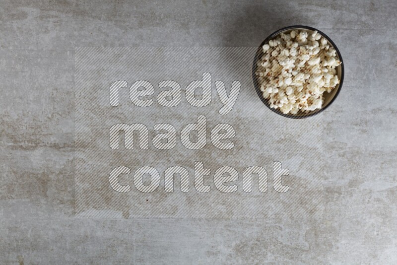 popcorn in a multi-colored pottery bowl on a grey textured countertop