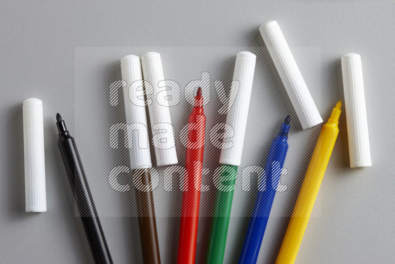 An arrangement of coloring pens in different colors on grey background