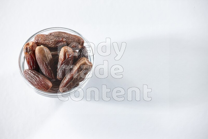 A glass bowl full of dried dates on a white background in different angles