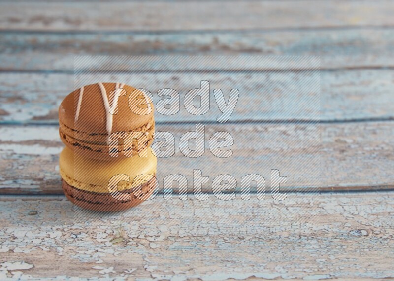 45º Shot of of two assorted Brown Irish Cream, and Yellow, and Brown Chai Latte macarons  on light blue background