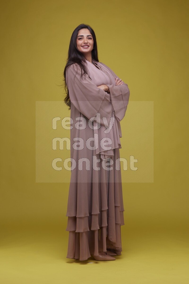 A woman Posing on a Yellow Background wearing Brown Abaya